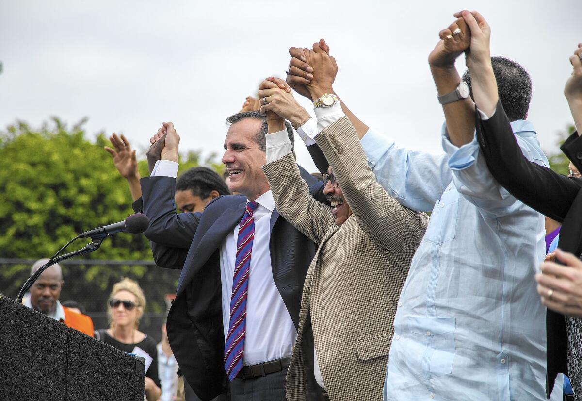 Mayor Eric Garcetti, left, raises arms with City Council President Herb Wesson, center, and Councilman Curren Price before signing into law L.A.'s plan to raise its minimum wage.