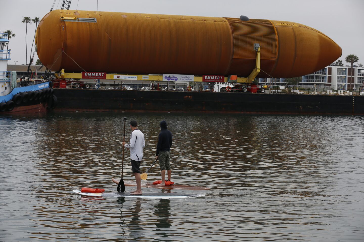 Paddleboarders watch as the space shuttle external fuel tank ET-94, the last of its kind, arrives in Marina del Rey.