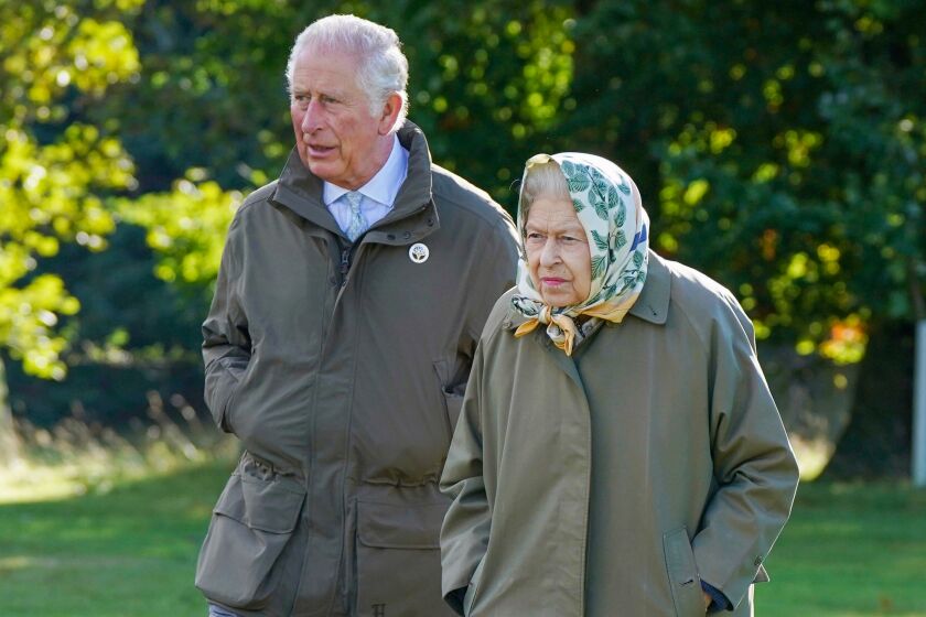 Britain's Queen Elizabeth II, right and Prince Charles walk to the Balmoral Cricket Pavilion in Balmoral, Scotland.