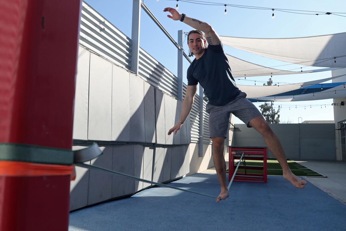 Chris Hoover, a Movement personal trainer, practices his balance on the slackline at Movement in Fountain Valley Wednesday.