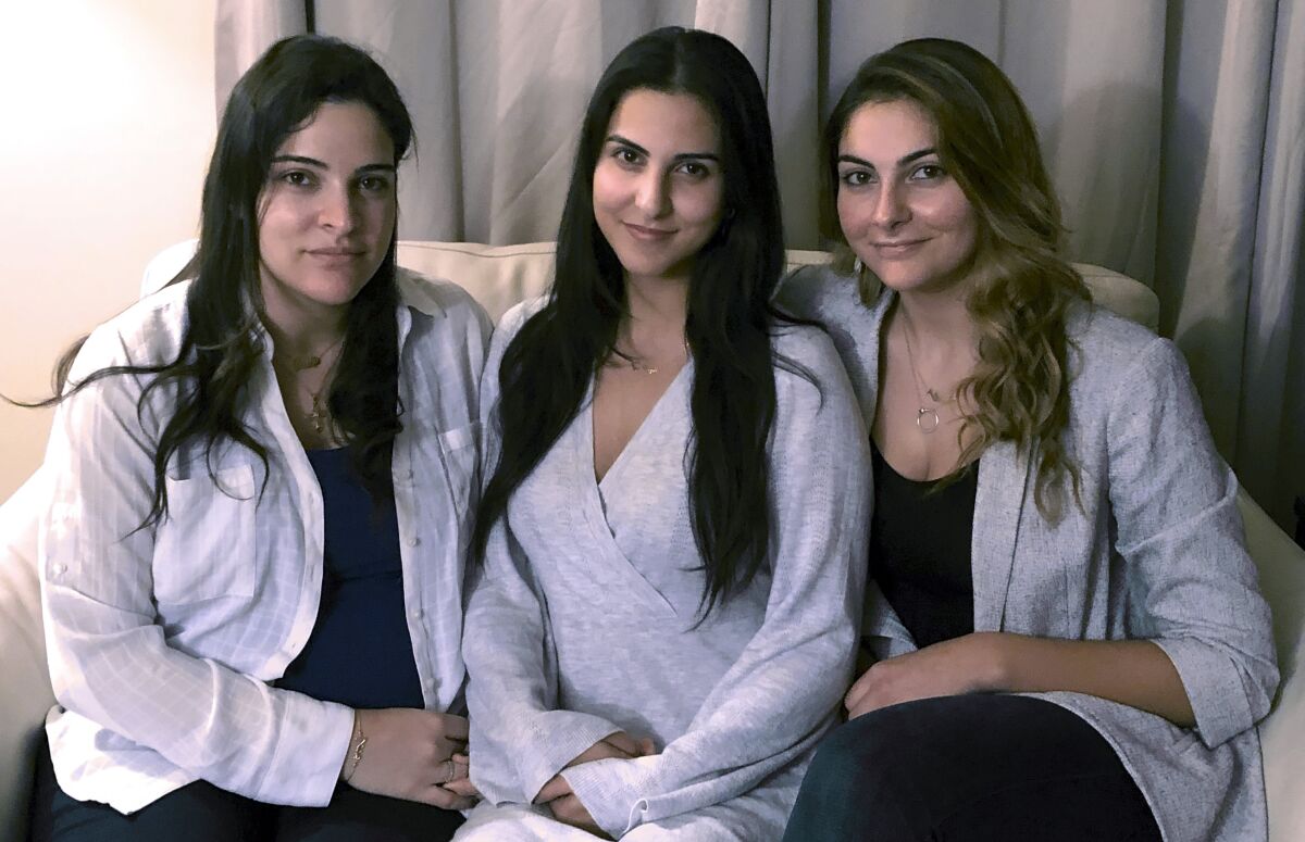 FILE — Three of Amer Fakhoury's four daughters, from left, Guila, Macy, and Zoya Fakhoury, gather Nov. 5, 2019, in Salem, N.H. Amer Fakhoury was a Lebanese American restaurant owner who made his first trip back to Lebanon in 2019 in nearly 20 years to see family. In Lebanon he was accused of torturing and killing inmates at a former prison where his family says he had worked as a clerk. Fakhoury was released in March 2020 and died that August from lymphoma. The Fakhourys are trying to sue Lebanon, as well as Iran, alleging mistreatment of their father. (AP Photo/Kathy McCormack, File)