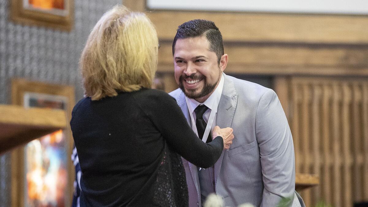 Mary Wickman places a nursing pin on a lanyard over the head of Miguel Rosado during a ceremony Thursday at Vanguard University in Costa Mesa.