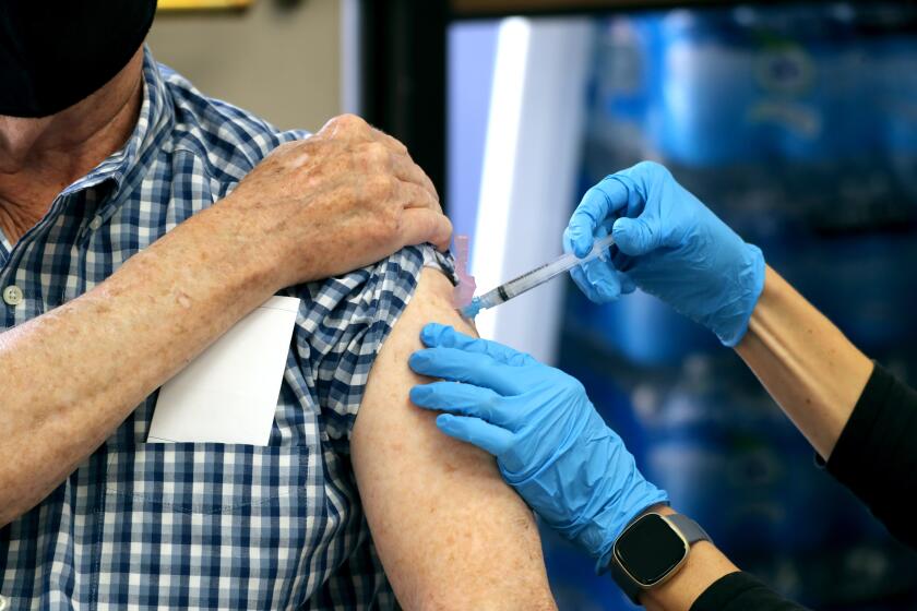 Veterinary doctor Robert Valentine, 75, gets his Covid-19 vaccine from Karen L. Simerlink, R.N., at the Central Net Training Center in Huntington Beach on Wednesday, Jan. 13, 2021. The vaccine is available by appointment to tier 1A individuals.