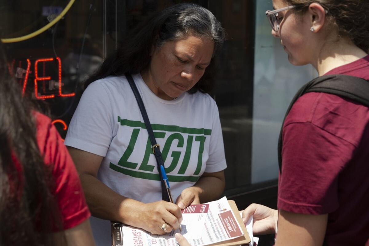 A woman signs papers on a clipboard