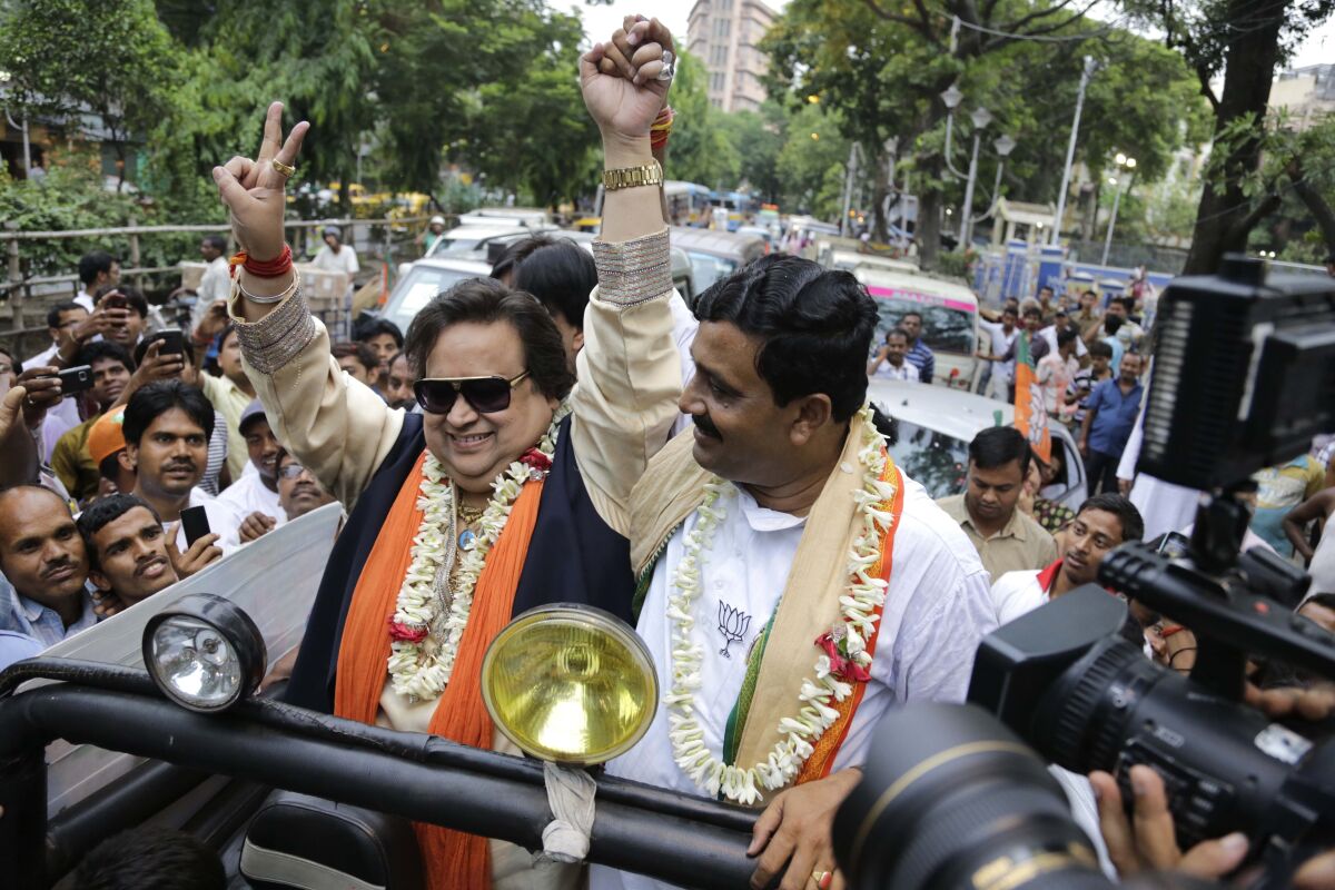 FILE- Bollywood singer and composer Bappi Lahiri, left, campaigns for Bharatiya Janata Party candidate Rahul Sinha, right, in Kolkata, India, May 3, 2014. Lahiri, who won millions of fans with his penchant for feet-tapping disco music in the 1980s and 1990s, has died in a Mumbai hospital, a hospital statement said. He was 69. (AP Photo/ Bikas Das, File)