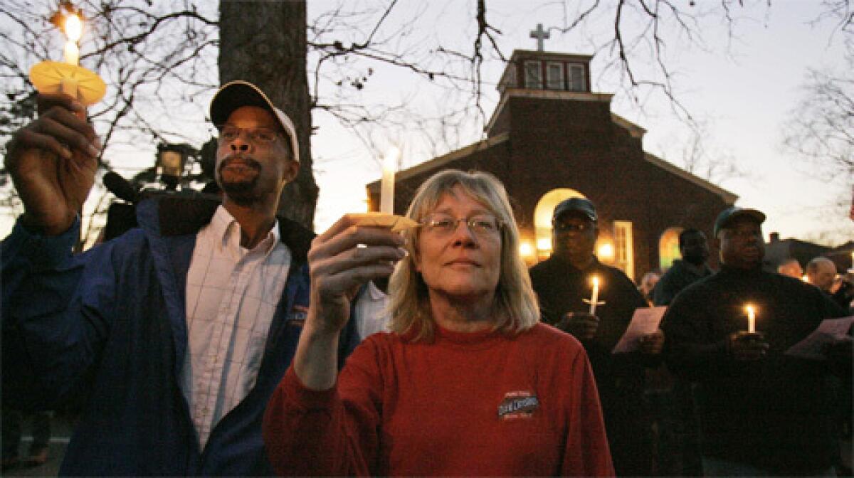 REMEMBRANCE: Darren Edwards, left, and Pat House join in a vigil for refinery explosion victims at Our Lady of the Lourdes Church in Port Wentworth, Ga. Theres not anyone in town who didnt know someone who worked there, one resident said.