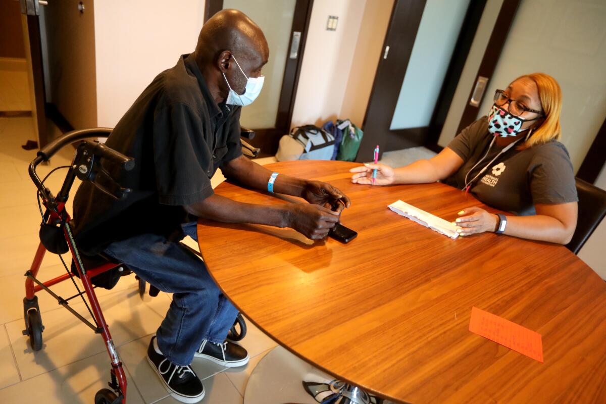 LVN Qiana Parhm, with National Health Foundation, right, consults with Project Roomkey guest David William, 63.