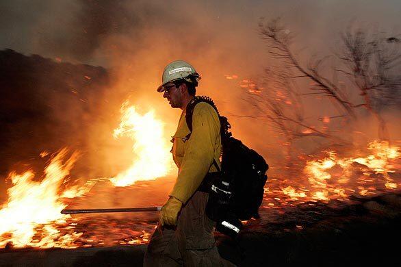 A firefighter walks along a control burn applied in the neighborhood of Pinecrest in La Crescenta. The fire was set to protect homes from the Station fire, which has charred 122,000 acres.