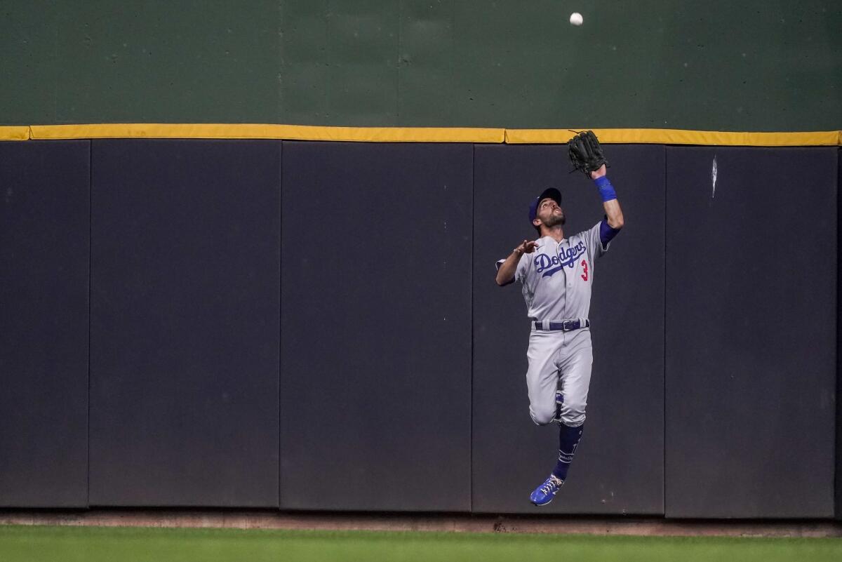 Dodgers center fielder Chris Taylor leaps to catch a ball hit by Milwaukee's Kolten Wong.