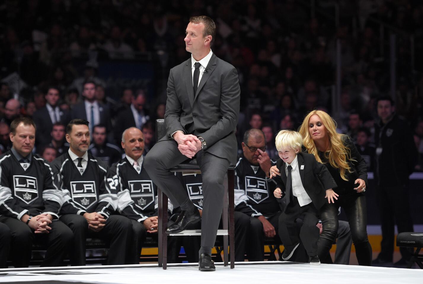 Former Kings defenseman Rob Blake listens to a speech during the ceremony to retire his jersey as his wife Brandy tries to keep their three-year-old son Max from running onto the stage.