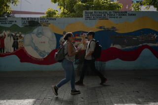 People walk in front of a politically charged mural near Bolivar Square. The Iranian Forest vessel depicted on the right side of the mural arrived in Venezuela during fuel shortages in 2020.