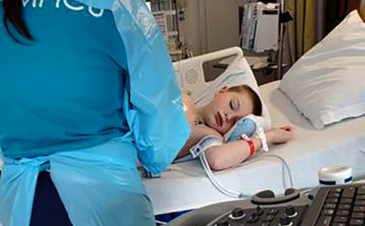 Nine-year-old Bobby Dean lies on a hospital bed in Rochester, N.Y., after being admitted with severe dehydration, abdominal pain and a racing heart. He tested positive for coronavirus at the hospital and the doctors diagnosed him with a pediatric inflammatory syndrome related to the virus.
