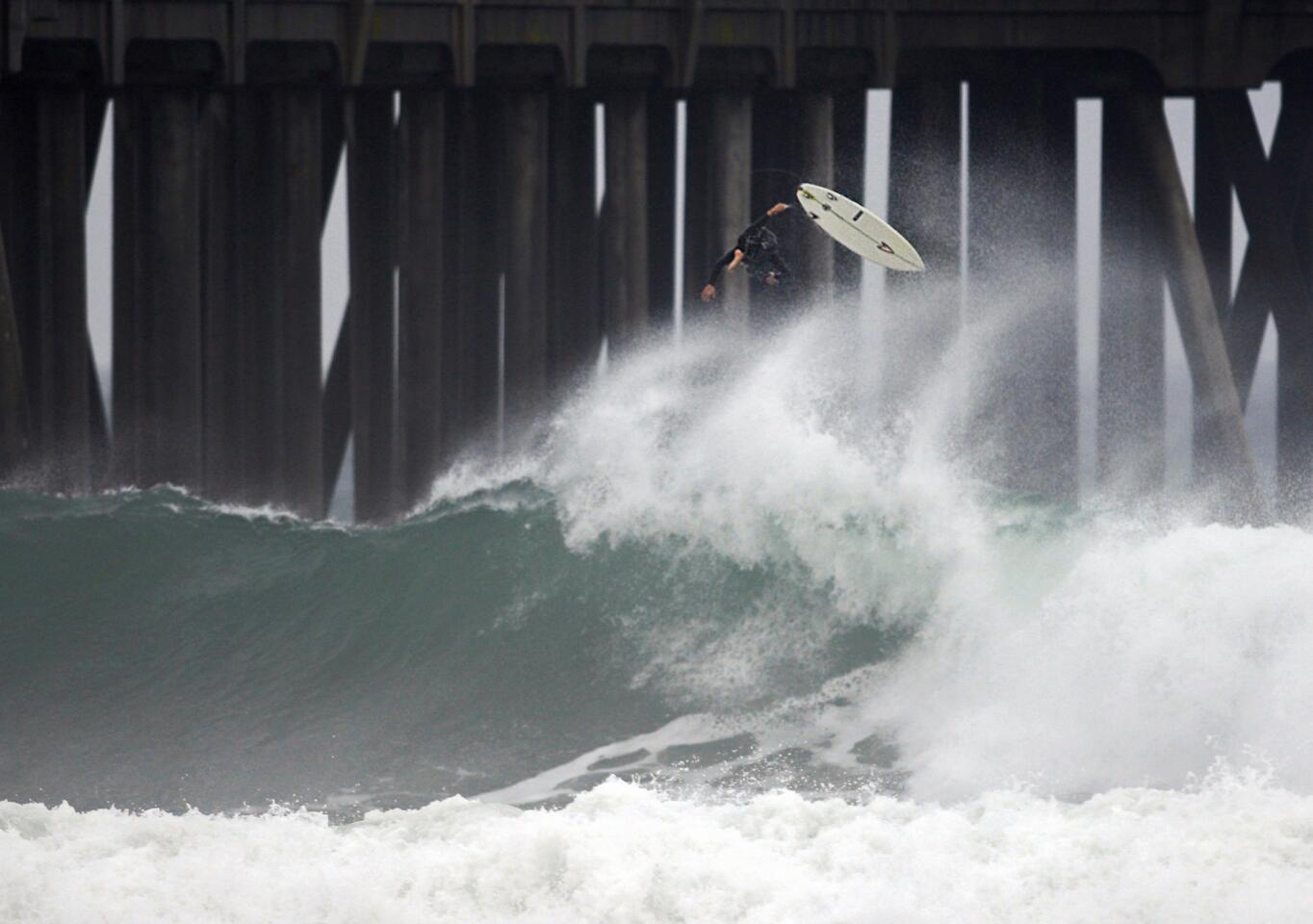 Amid light rain, a surfer bails out after riding a big wave in Huntington Beach.