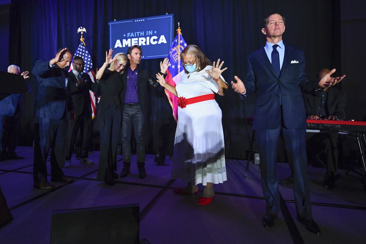 FILE - In this July 23, 2020, file photo, from right, Faith & Freedom Coalition founder Ralph Reed, Dr. Alveda King, Journey keyboardist Jonathan Cain, and White House faith adviser Paula White-Cain, and others pray on stage during an Evangelicals for Trump campaign event titled "Praise, Prayer and Patriotism" in Alpharetta, Ga. President Donald Trump’s reelection campaign is courting religious voters in part by seeking to portray Democrats as a threat to religious freedom — a pitch amplified by disputes over the issue during the coronavirus pandemic. (AP Photo/John Amis, File)