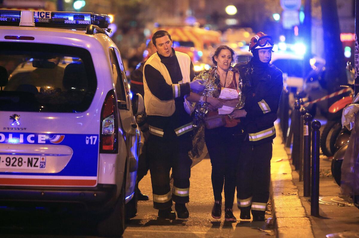 FILE - In this Nov. 13, 2015, file photo, rescue workers help a woman after an attack by Islamic State militants, outside the Bataclan theater in Paris. On Nov. 13, 2015, a cell of nine Islamic State militants armed with automatic rifles and explosive vests left a trail of dead and injured at the national stadium, Paris bars and restaurants and the Bataclan concert hall. Nearly all the attackers were from France or Belgium, as were the cell's 10th member — the only one still alive. He is the chief defendant among 20 people charged in a trial that is expected to last nine months. (AP Photo/Thibault Camus, File)