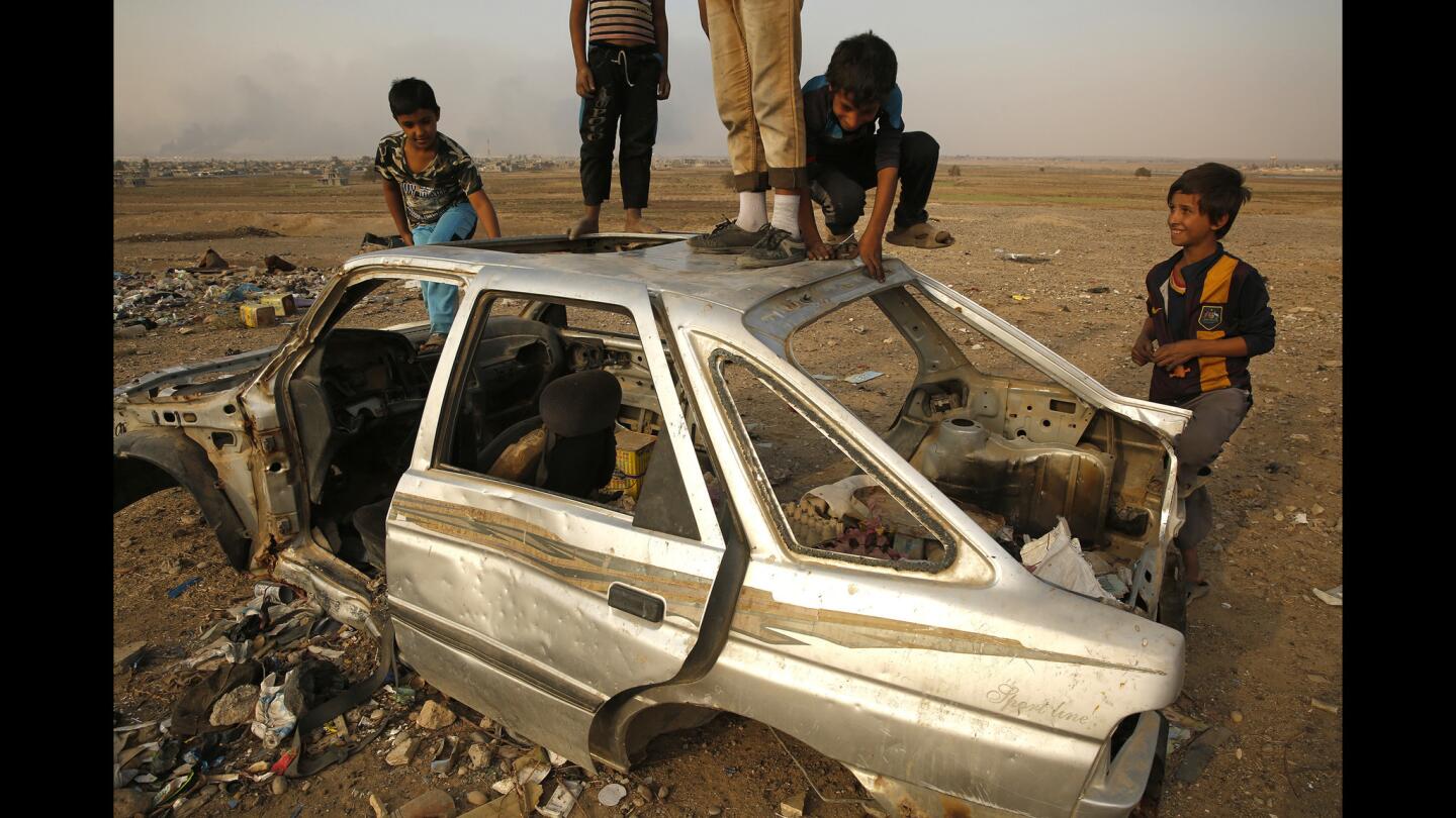 Children play in a wrecked car in the village of Hurriya, where fighting between Islamic State and Iraqi forces caused many families to leave.