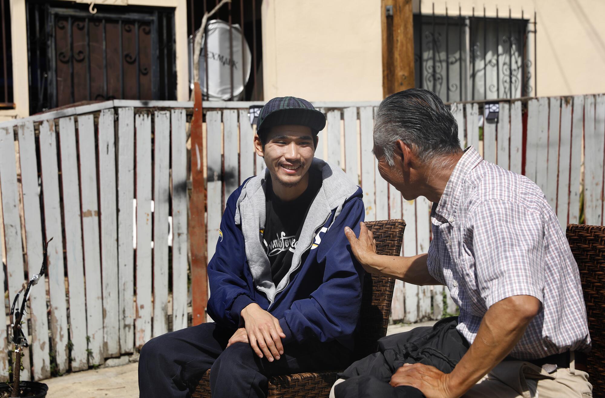 Aron Mey, left, chats with resident Pedro Villegas, right.