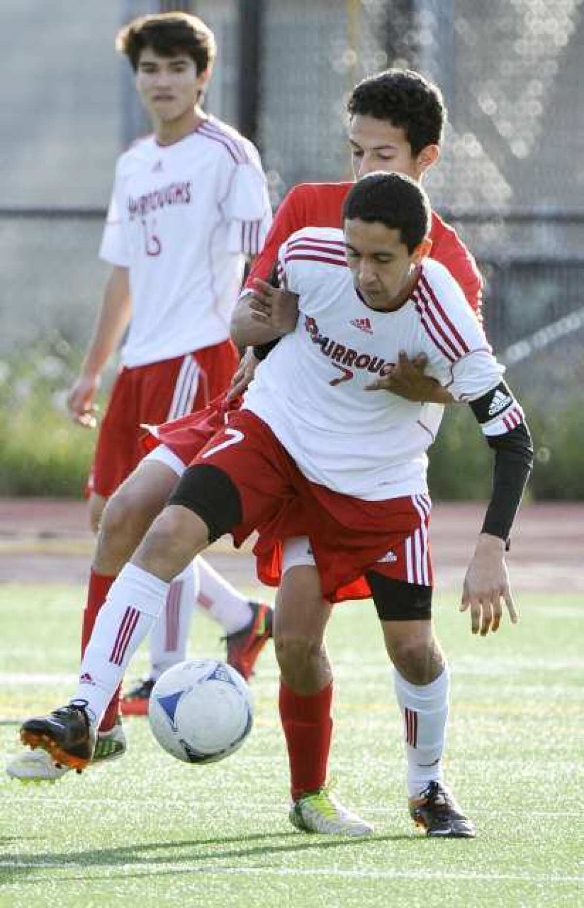 Burroughs' Brian Arzate, with Pasadena defender Gerardo Espinoza reaching through him, controls the ball in the first half in a Pacific League boys soccer match at Burroughs High School in Burbank on Monday, January 28, 2013. Pasadena won the match 3-1. (Tim Berger/Staff Photographer)