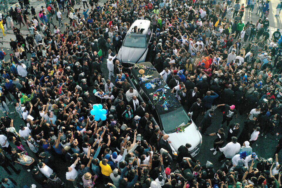 A hearse carrying the casket of Nipsey Hussle drives through a huge throng near his clothing store on Slauson Avenue in South Los Angeles.