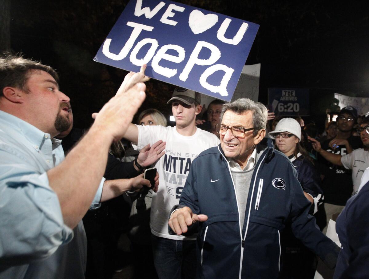 Then-Penn State coach Joe Paterno is greeted by his son Scott, left, and supporters as he arrives at his home in State College, Pa., on Nov. 8, 2011. He was fired the next day by university trustees amid the Jerry Sandusky sexual abuse scandal.