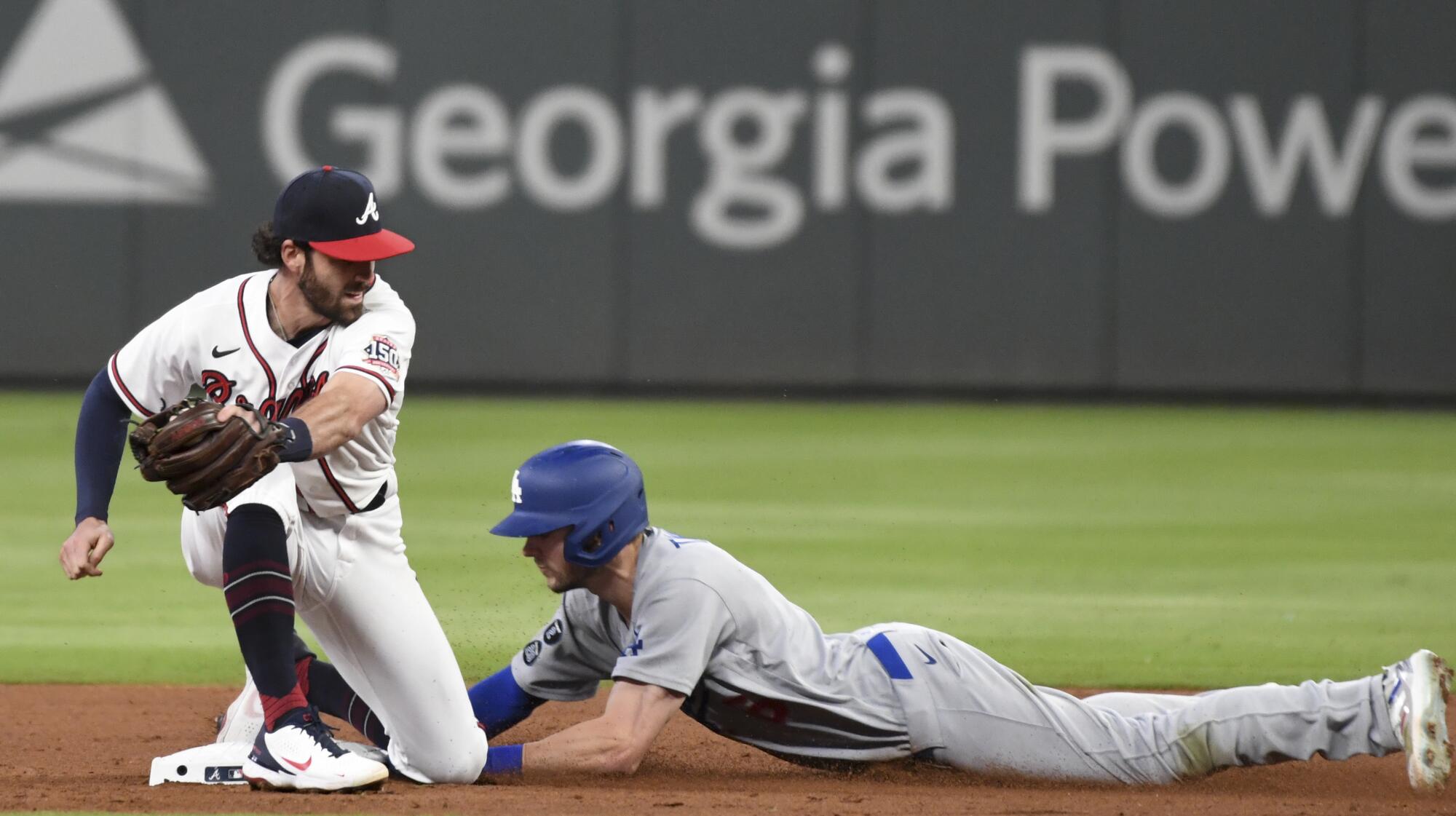 Dodgers' Trea Turner slides into second ahead of the tag from Braves shortstop Dansby Swanson to steal second base