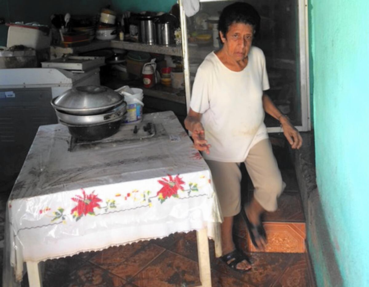 Genoveva Salcedo, 67, gingerly steps through her muddy home in Cihuatlan, Mexico, after Hurricane Patricia struck.