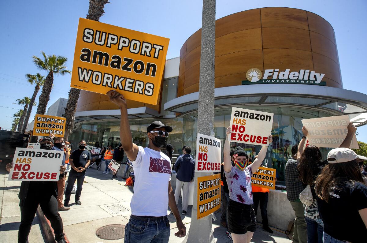 Supporters of Amazon workers hold signs at a protest outside a Fidelity Investments office.