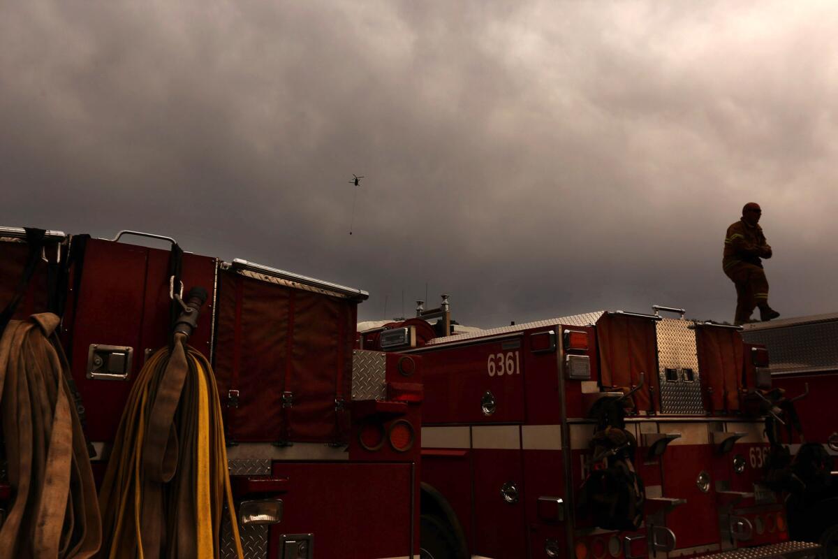 A firefighter walks on top of a fire engine as rain begins to fall in Lake County just south of Clear Lake on Tuesday.