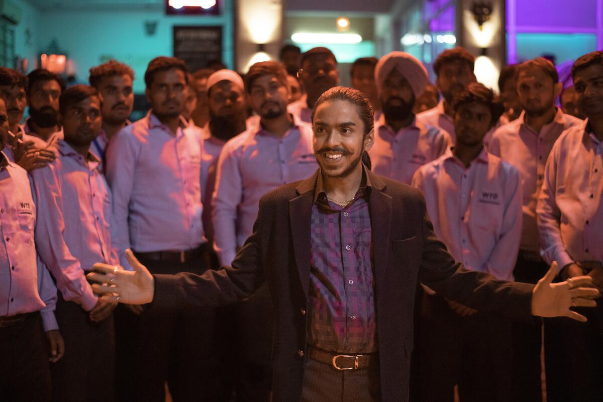 A smiling man stands before a crowd of men in white buttondown shirts.