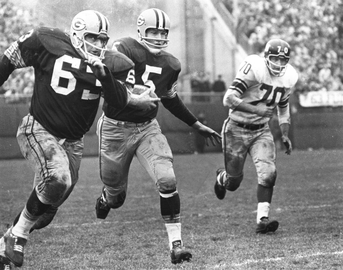 Green Bay offensive lineman Fuzzy Thurston, left, leads running back Paul Hornung on a sweep during a 1961 game.