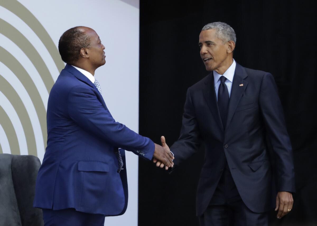 FILE - In this file photo dated Tuesday, July 17, 2018, former US President Barack Obama, right, shakes hands with Patrice Motsepe, as he arrives at the Wanderers Stadium in Johannesburg, South Africa, to deliver the 16th Annual Nelson Mandela Lecture. The election to lead African soccer is seeming to be dominated by FIFA president Gianni Infantino, who supports South African billionaire Patrice Motsepe to win the top job in a ballot next week. (AP Photo/Themba Hadebe, FILE)