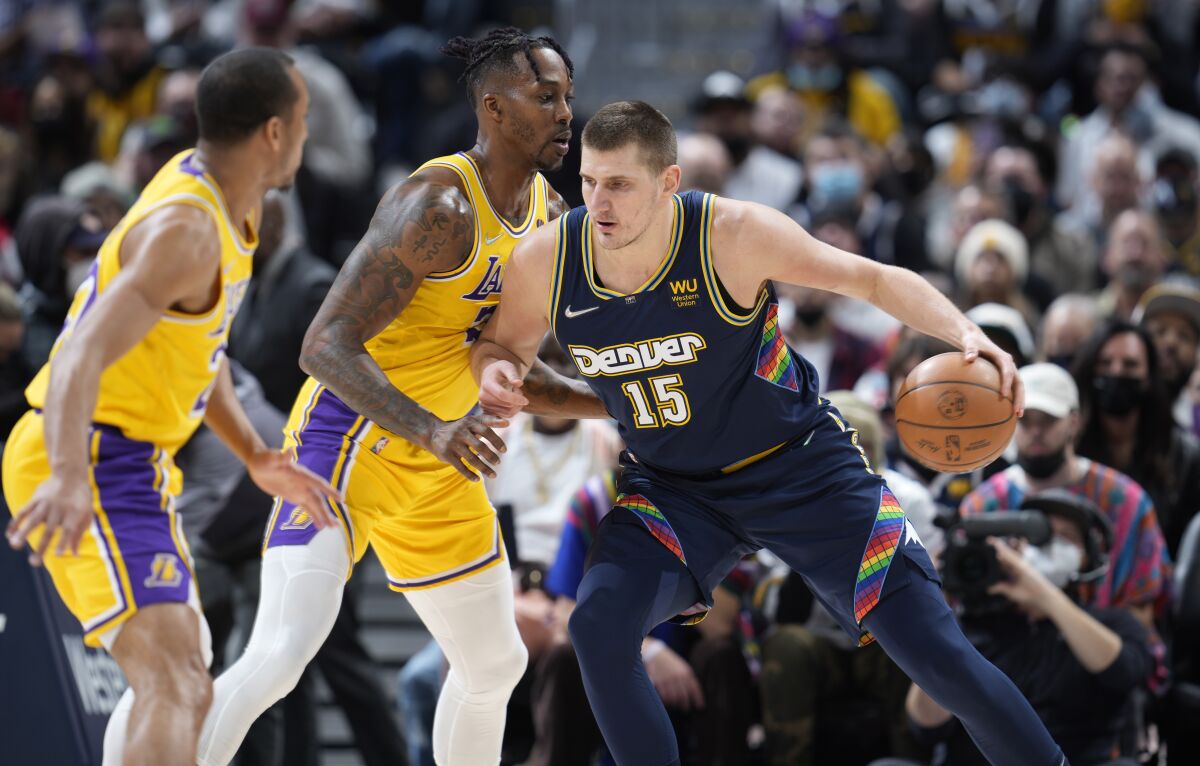 Denver Nuggets center Nikola Jokic, right, works the ball inside as Los Angeles Lakers guard Avery Bradley, left, and center Dwight Howard defend in the first half of an NBA basketball game Saturday Jan. 15, 2022, in Denver. (AP Photo/David Zalubowski)