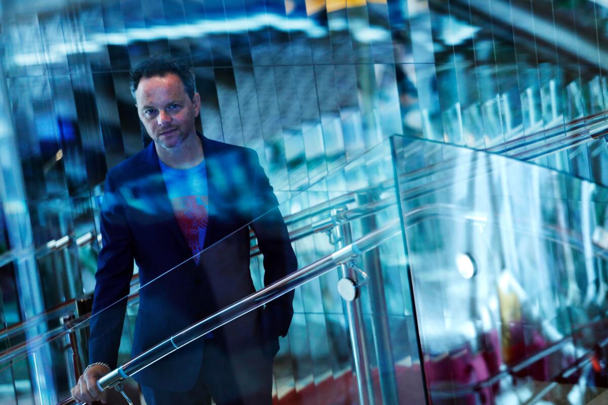 Noah Hawley portrait shot with blue tints among glass walls.