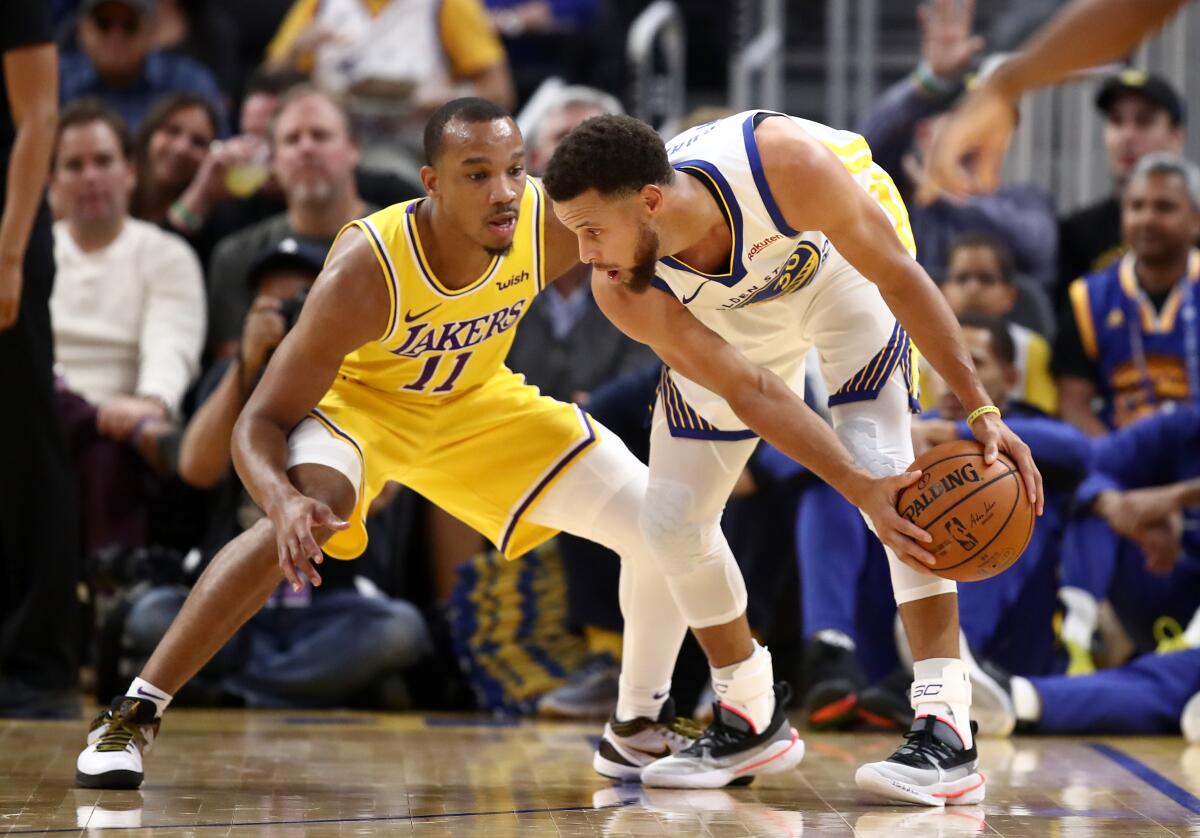 Lakers point guard Avery Bradley defends Warriors All-Star Stephen Curry during a preseason game.