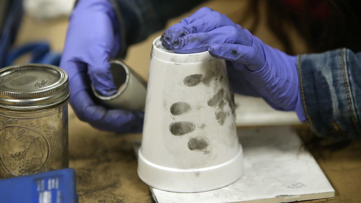 Participants in a crime scene investigation class learn to dust and reveal a fingerprint on a cup as part of the Costa Mesa Citizens’ Police Academy.