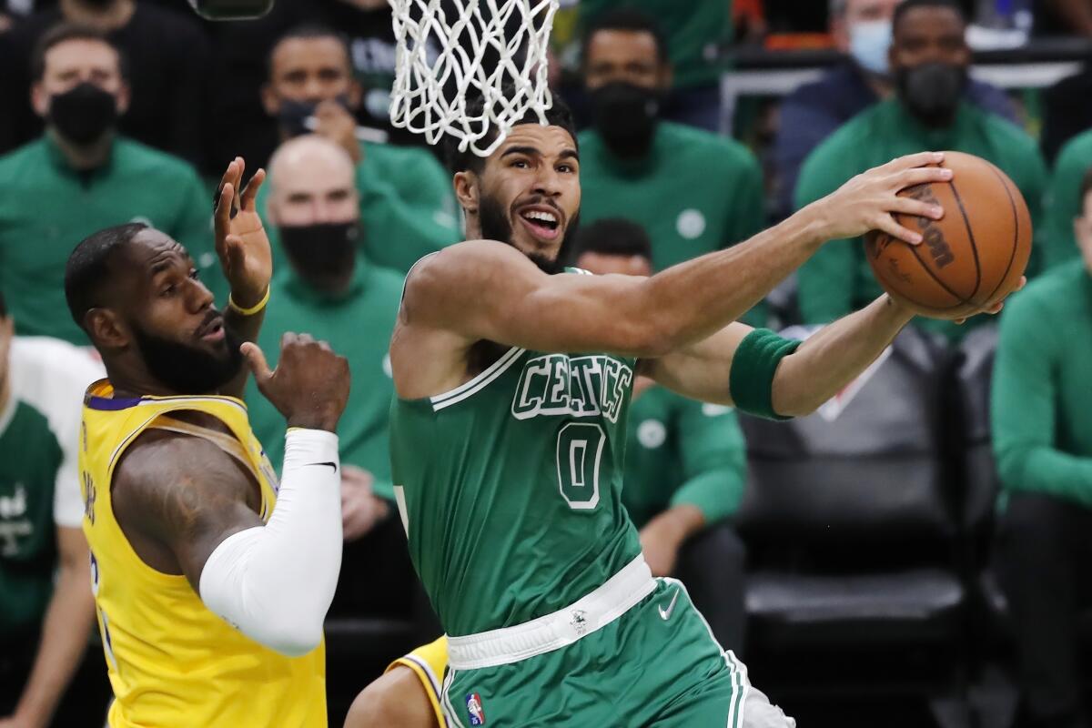 Jayson Tatum (0), de los Celtics de Boston, ataca el aro ante la marca de LeBron James, izquierda, de los Lakers.