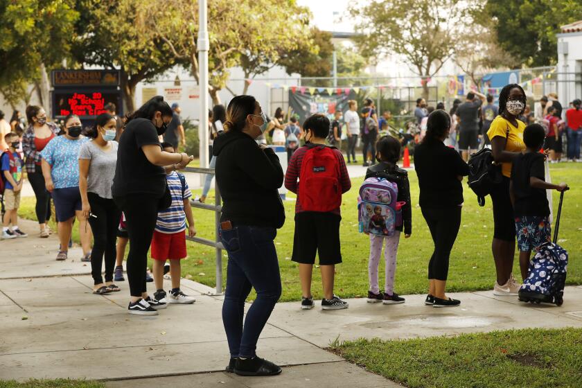 NORTH HOLLYWOOD, CA - AUGUST 17: Parents and students form lines to check for the student name on a list using the Daily Pass website - designed to issue pre-approved health clearances for students to enter campus or present their QR code for entrance to the campus at Lankershim Elementary School in North Hollywood on Tuesday for the second day of in-class learning for LAUSD schools. The pre-approved health clearances for students to enter campus appeared to be up and working so the second day of school in the Los Angeles Unified School District appears to be going more smoothly than the first, largely devoid of the long lines and frustrations on back-to-school Monday when the district's student health-check system failed. Lankershim Elementary on Tuesday, Aug. 17, 2021 in North Hollywood, CA. (Al Seib / Los Angeles Times).