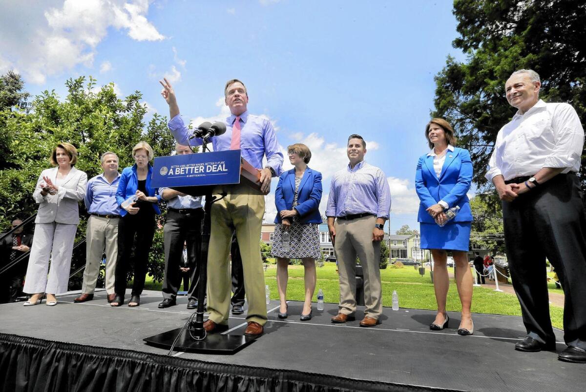 Virginia Sen. Mark Warner, surrounded by other key Democrats, speaks Monday about the party’s new slogan and economic plan in Berryville, Va.