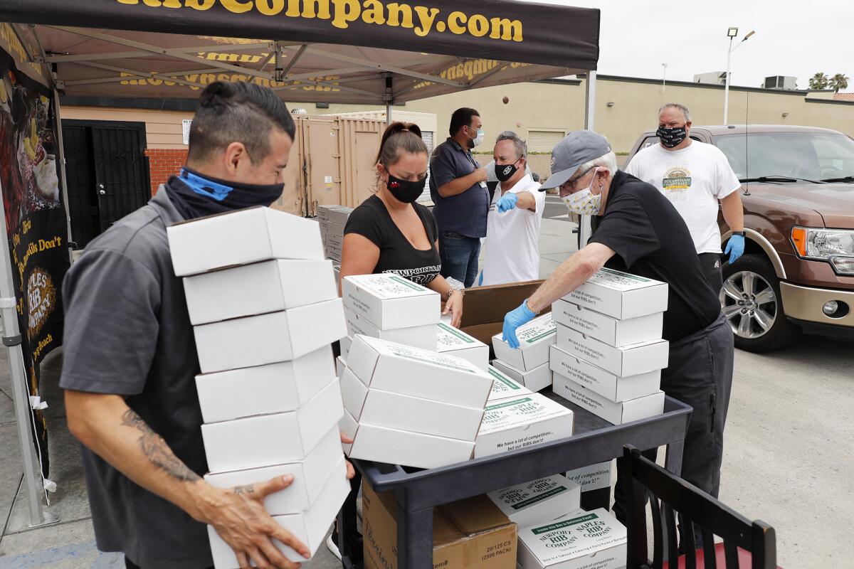 Newport Rib Company employees and Costa Mesa United volunteers restock and organize box meals to hand out Tuesday.