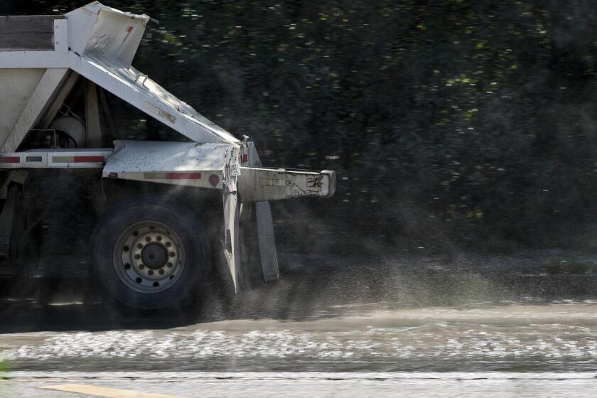 A truck creates a fine muddy mist as it heads out with a load of dirt from the Hahamongna Watershed Park L.A. County Public Works Department's Devil's Gate Dam Sediment Removal project, in La Canada Flintridge on Tuesday, July 30, 2019.