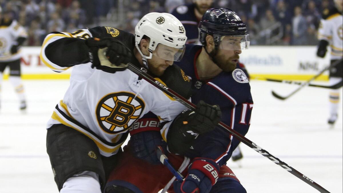 Boston Bruins defenseman Matt Grzelcyk, left, and Columbus Blue Jackets forward Brandon Dubinsky chase after a loose puck during Game 3 of the NHL Eastern Conference semifinals on April 30.