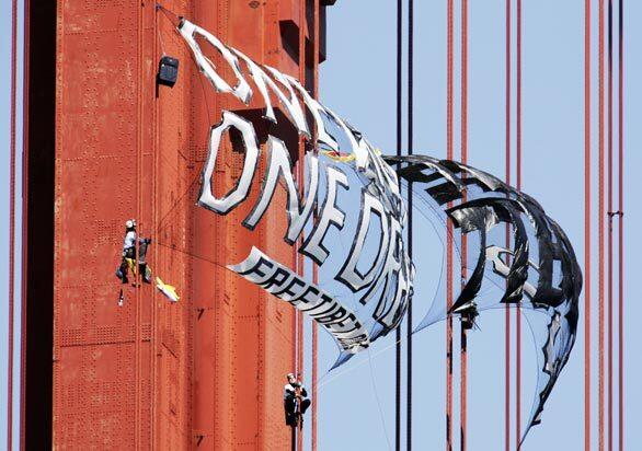 Two of three demonstrators protesting China's human rights record and the impending arrival of the Olympic torch tie Tibetan flags and two banners to the cables of the Golden Gate Bridge.