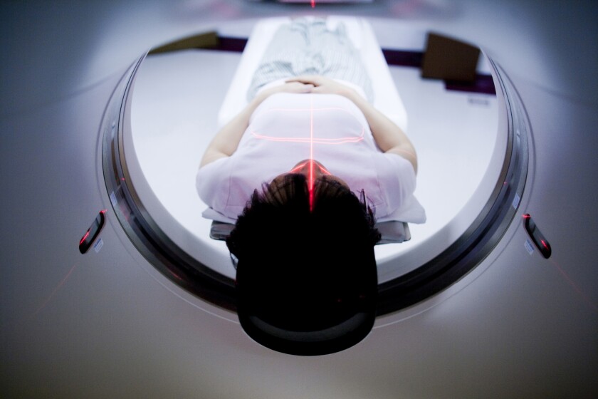 A person lies flat in a medical scanner
