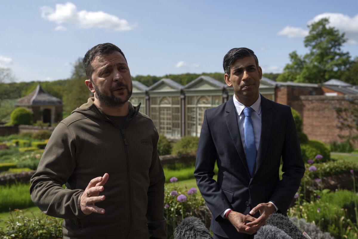 Ukrainian President Volodymyr Zelensky, left, and British Prime Minister Rishi Sunak stand in a garden.