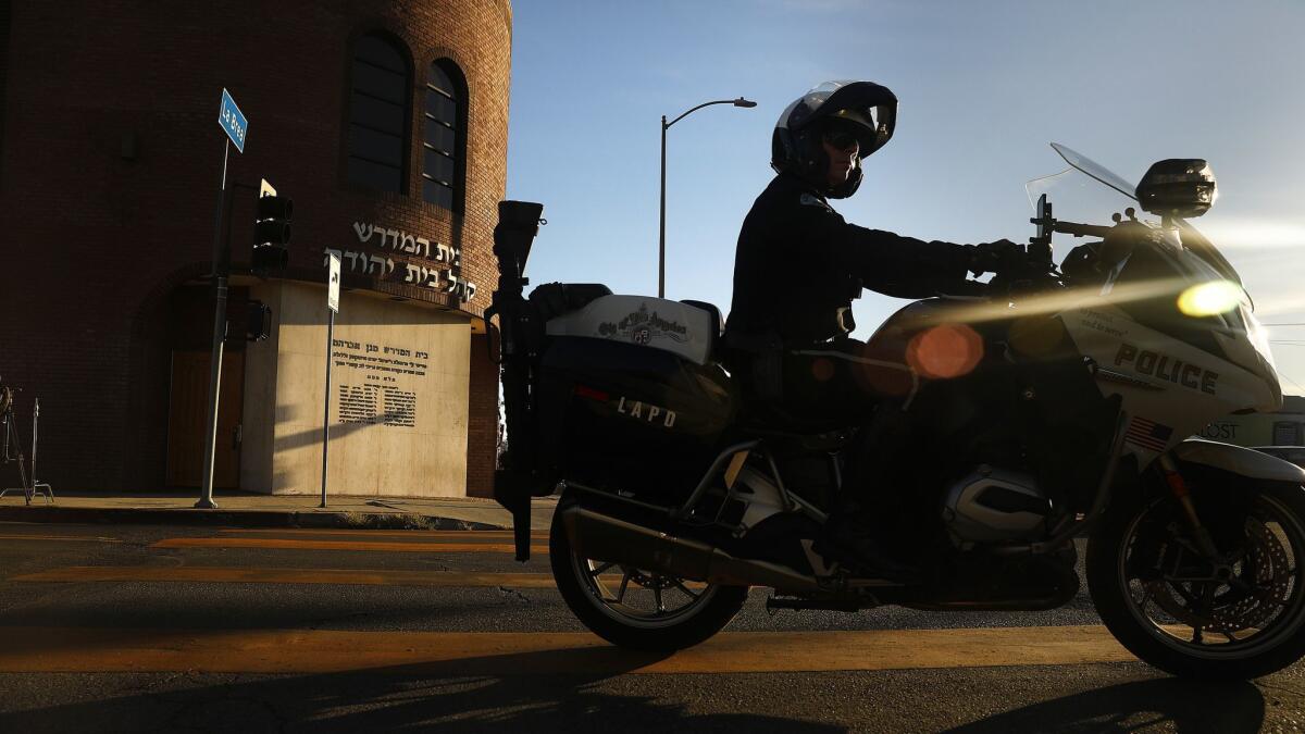 An LAPD motorcycle officer rides past Congregation Bais Yehuda on Monday in Hancock Park.