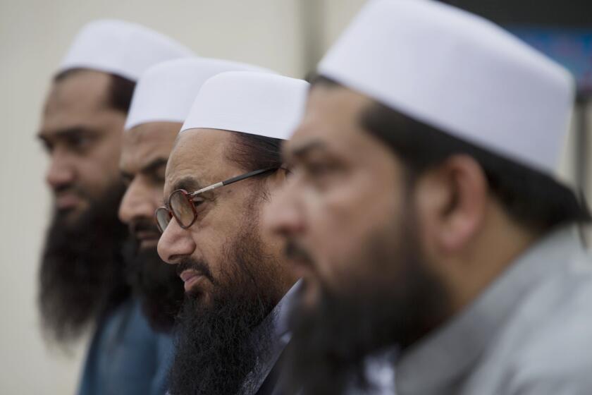 FILE- In this Monday, Nov. 2, 2015 file photo, Hafiz Saeed, second from right, chief of Pakistani religious group Jamaat-ut-Dawa listens to reporters at a news conference in Islamabad, Pakistan. Reports have surfaced in the Pakistani city of Lahore that a charity run by the militant group Lashkar-e-Taiba has established an Islamic court separate from the regular judiciary. The spokesman of the Jamaat-ud-Dawa charity claims it's not a parallel judicial system but that the court works with the consent of two rival parties to decide disputes. (AP Photo/B.K. Bangash, File) ORG XMIT: BKB104