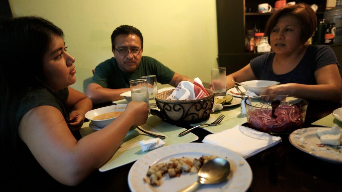 Brenda Soriano, left, converses with her parents Bertha Martinez and Victor Soriano during dinner in their apartment.