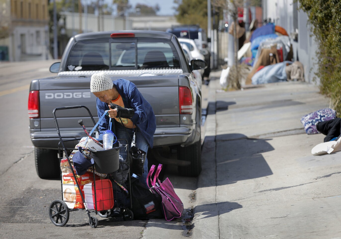 Marcella who has been homeless for the past five-years arranges some of her belongings while next to Triple K Manufacturing on Commercial Street in Sherman Heights where she sleeps. Residents and business owners are concerned the situation of homeless in the area will get worse if the city of San Diego opens a proposed storage facility for the homeless two blocks away.