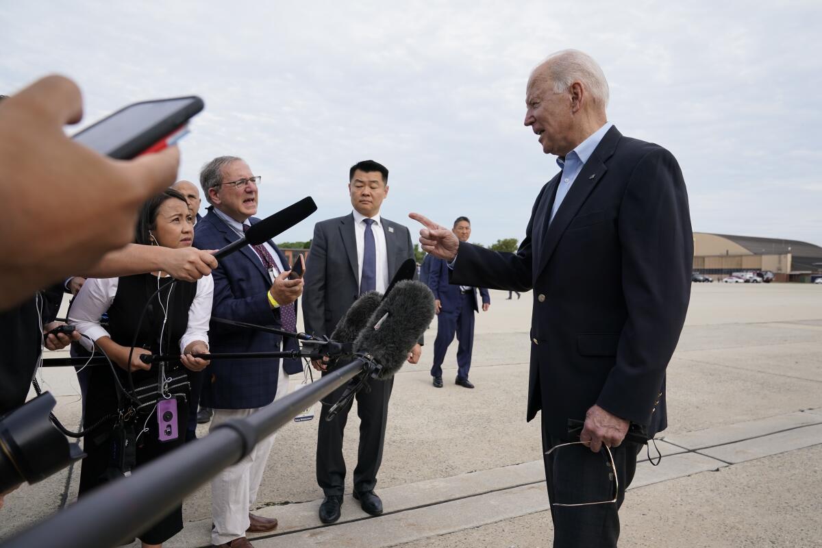 President Biden talks to a line of reporters on tarmac.