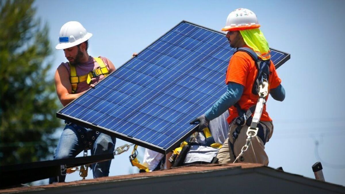 Workers install a solar panel array on a home in San Diego in 2017.